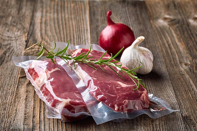 Filetes de carne envasados al vacío sobre una mesa de madera