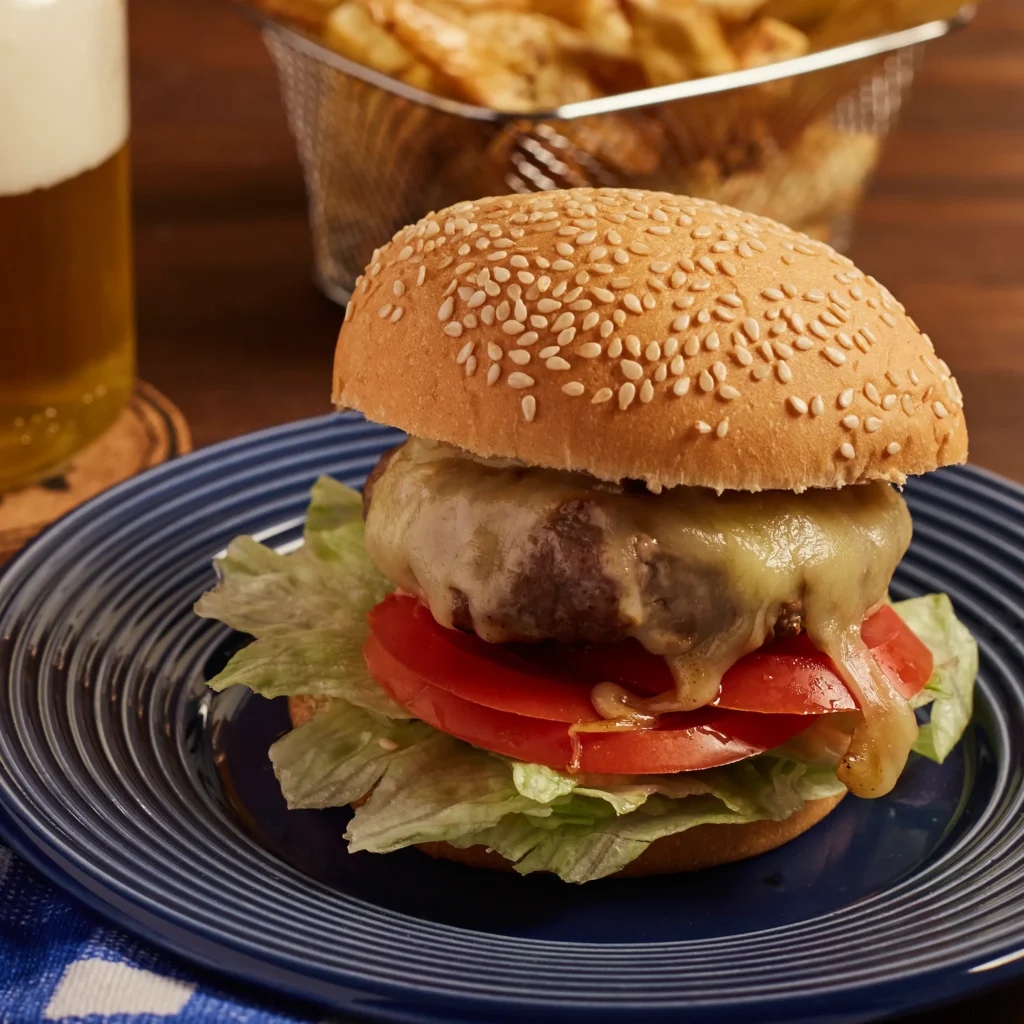 Hamburguesa con queso servida en plato con patatas fritas